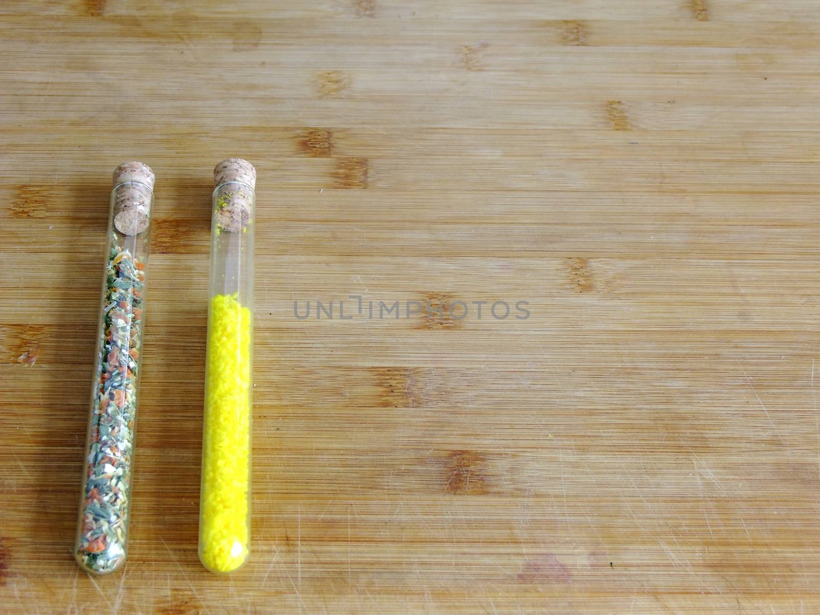 Spices in glass tubes  on left Side of wooden Cutting Board