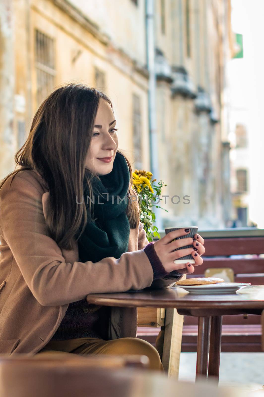 beautiful girl drinking coffee in a cafe on the street