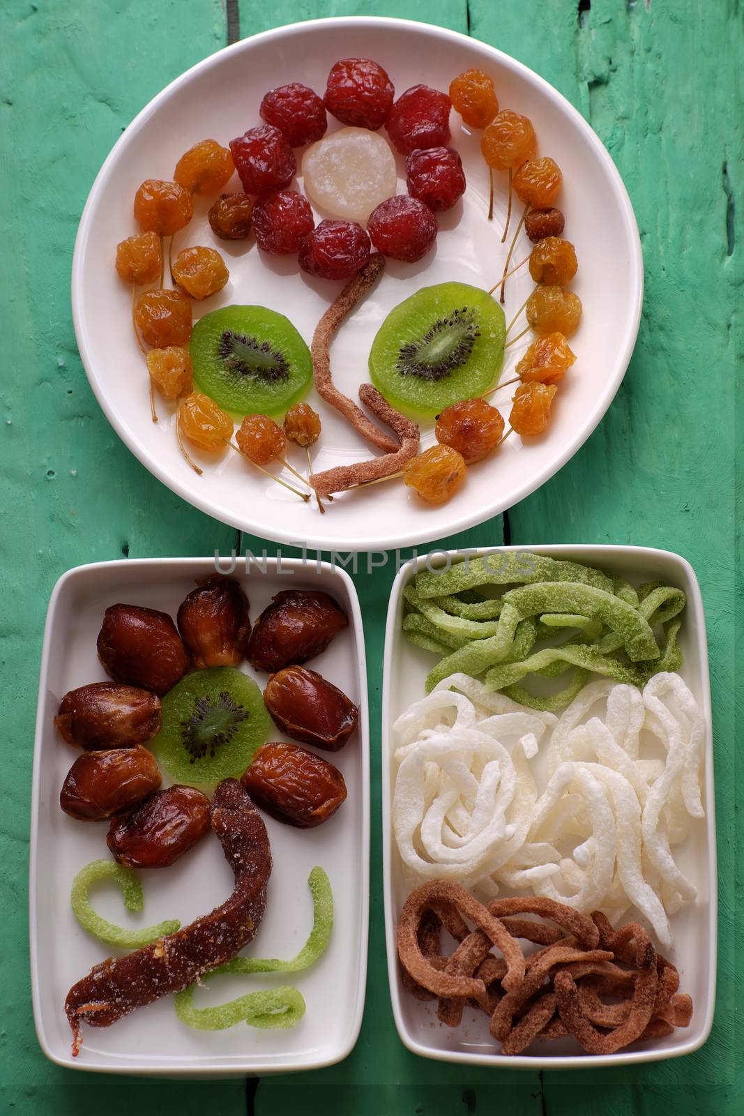 Group of colorful Vietnamese jam for Vietnam Tet holiday on green background, also lunar new year of Asia, traditional preserved fruit from kiwi, damson or coconut jam