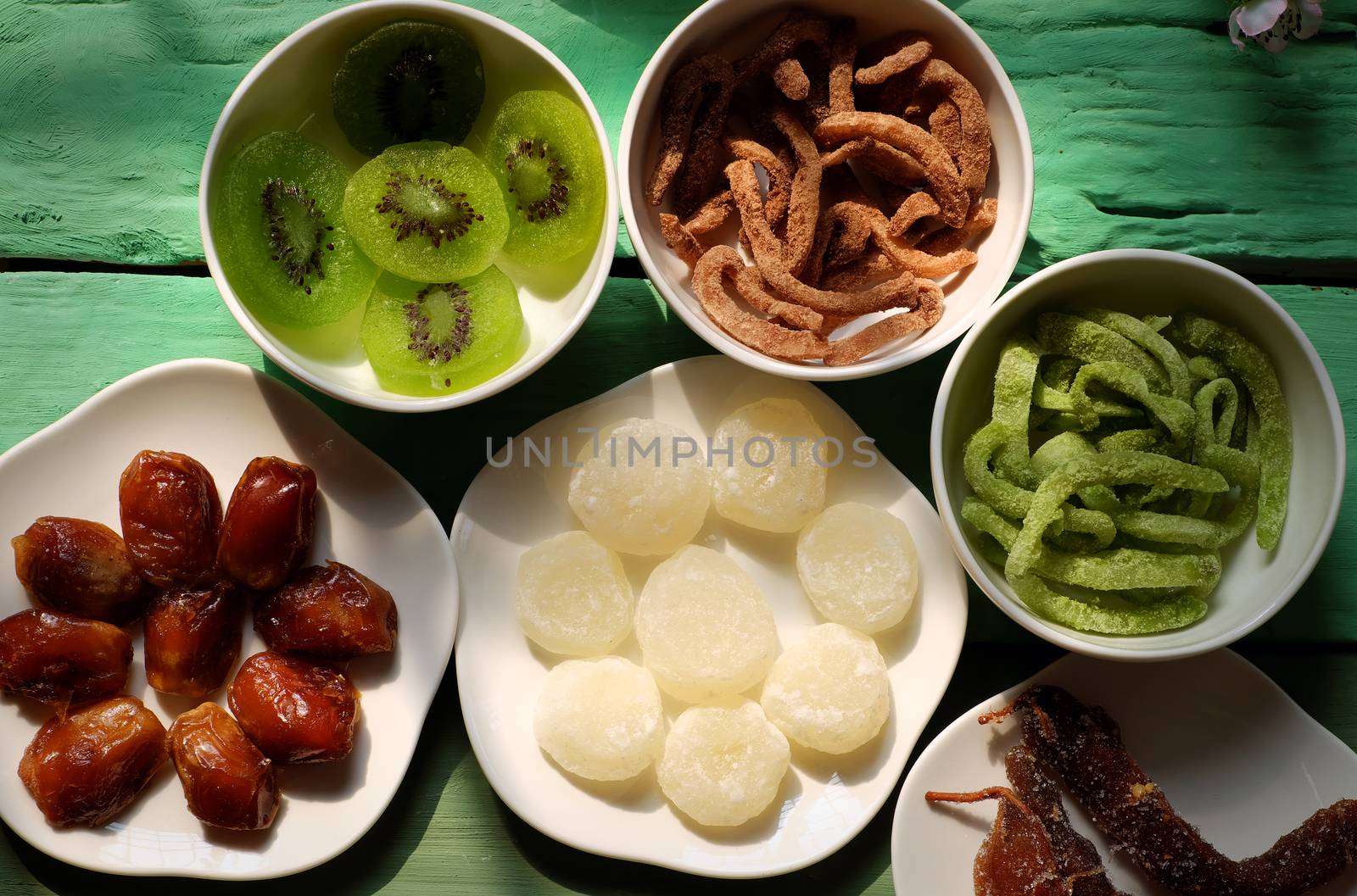 Group of colorful Vietnamese jam for Vietnam Tet holiday on green background, also lunar new year of Asia, traditional preserved fruit from kiwi, damson or coconut jam