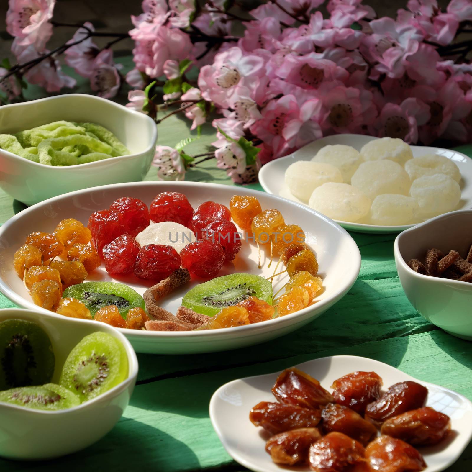 Group of colorful Vietnamese jam for Vietnam Tet holiday on green background, also lunar new year of Asia, traditional preserved fruit from kiwi, damson or coconut jam