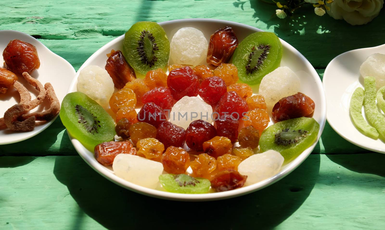 Close up of colorful Vietnamese jam for Vietnam Tet holiday on green background, also lunar new year of Asia, traditional preserved fruit from kiwi, damson or coconut jam