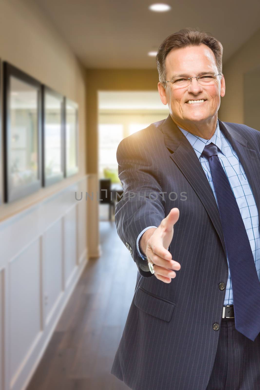 Smiling Male Agent Reaching for Hand Shake in Hallway of Beautiful New House.