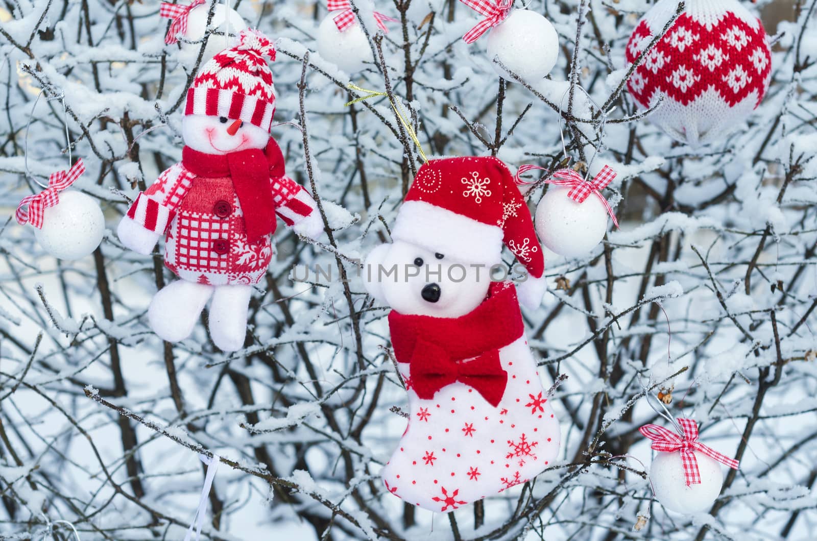 Christmas ornament snowman and bear on the snowy tree branches.