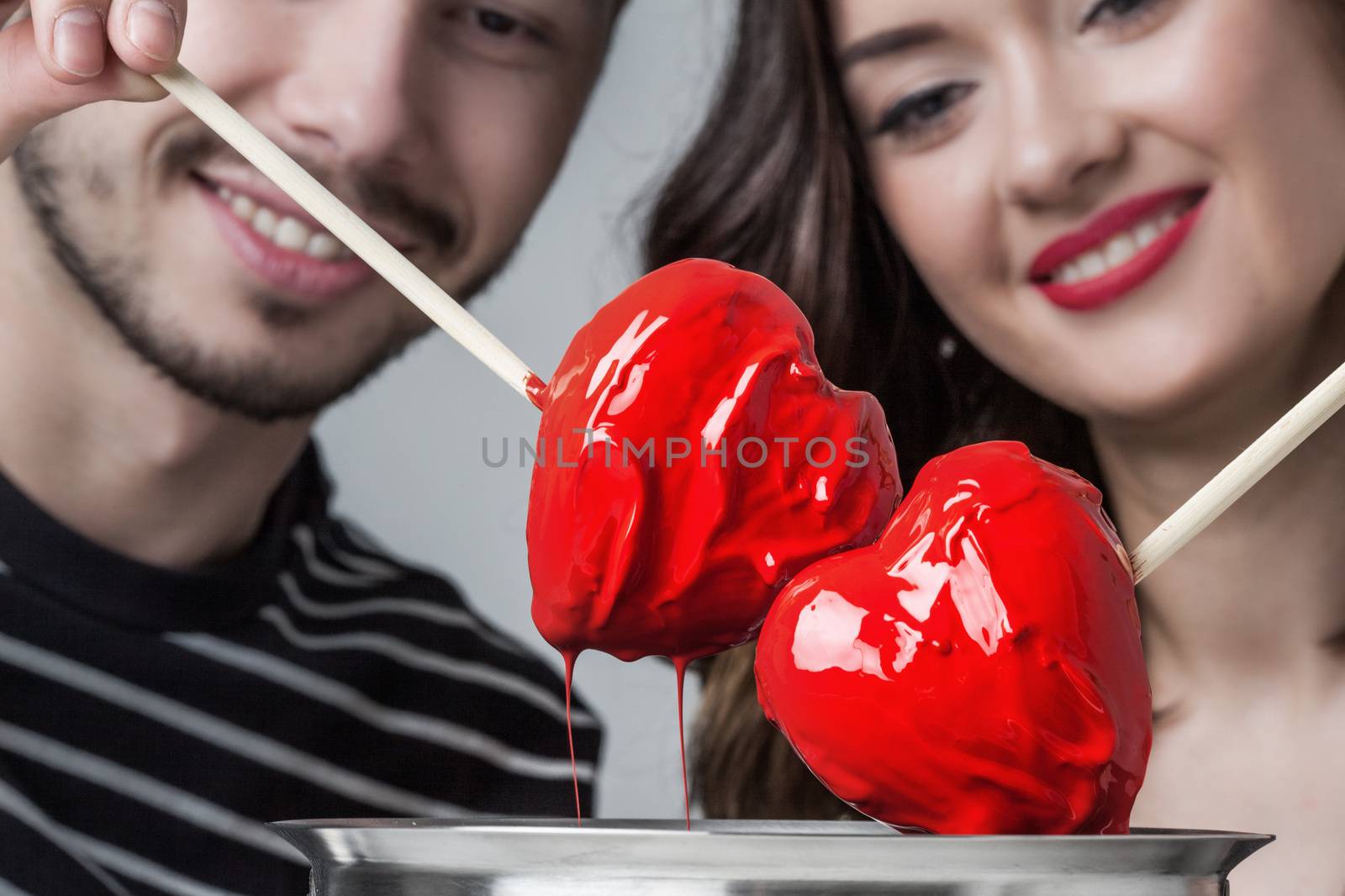 Fondue of love, loving couple dips chocolate hearts in red glaze