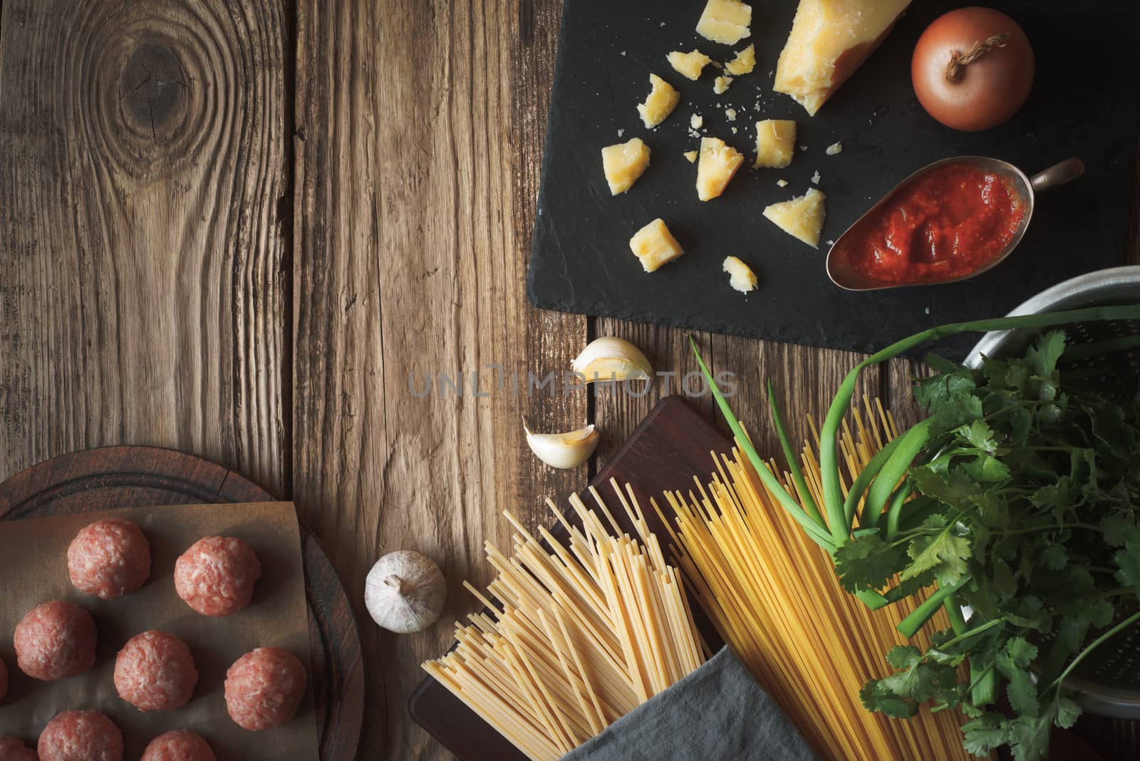 Ingredients for cooking spaghetti, meatballs with cheese and fresh herbs on the table horizontal copy space