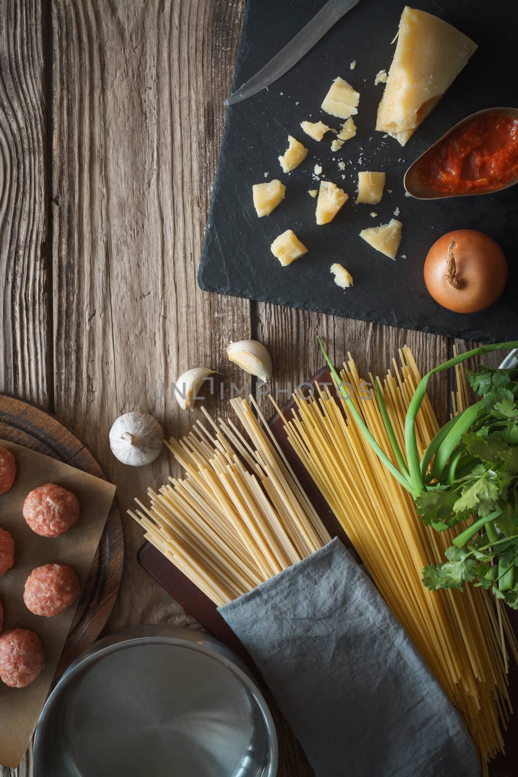 Ingredients for cooking spaghetti, meatballs with cheese and fresh herbs on the old table by Deniskarpenkov