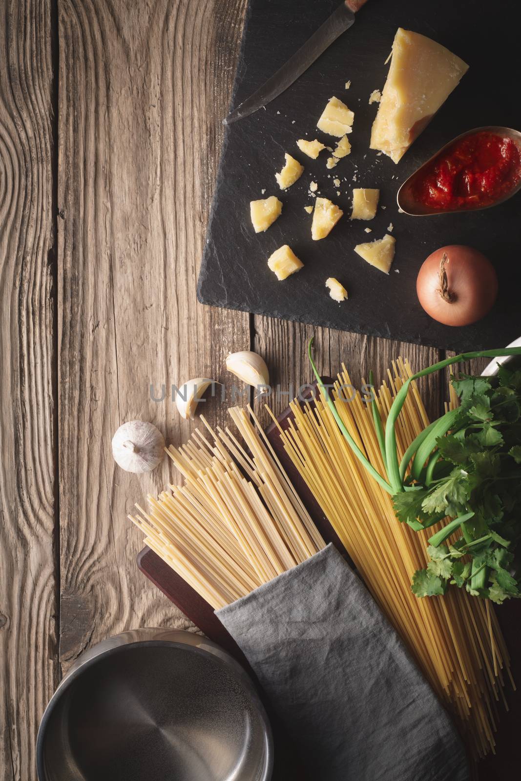 Ingredients for cooking spaghetti with cheese and fresh herbs on the old table by Deniskarpenkov