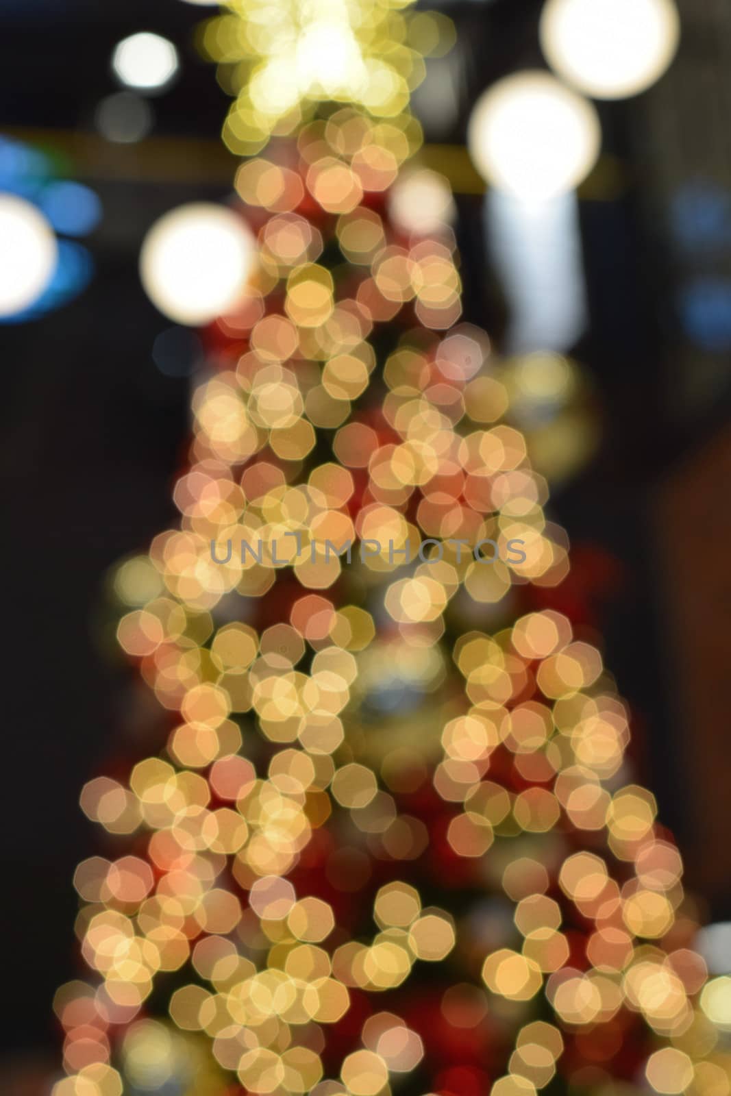 Holiday background - Large Christmas tree blurred lights in vertical frame