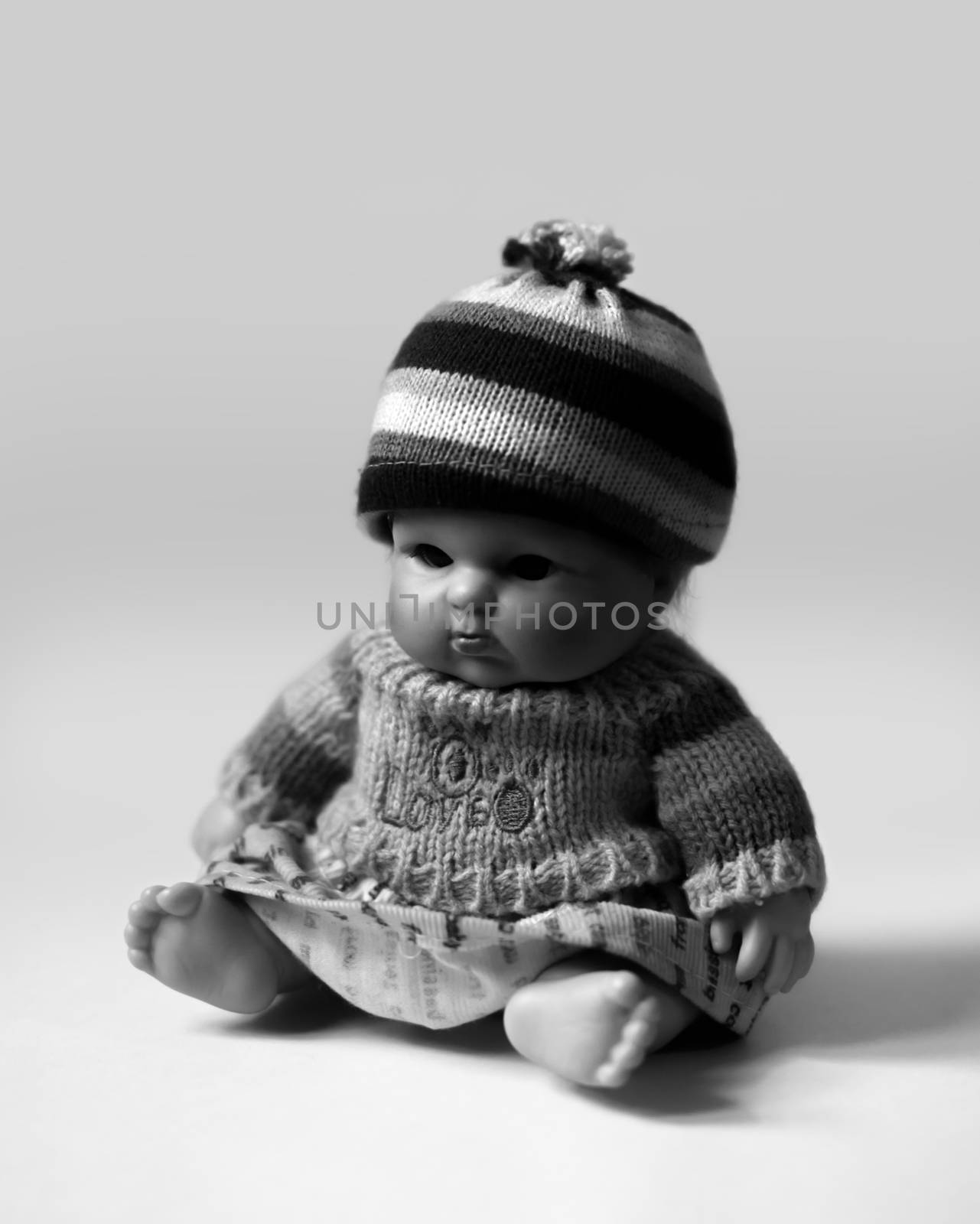 BLACK AND WHITE PHOTO OF SITTING DOLL