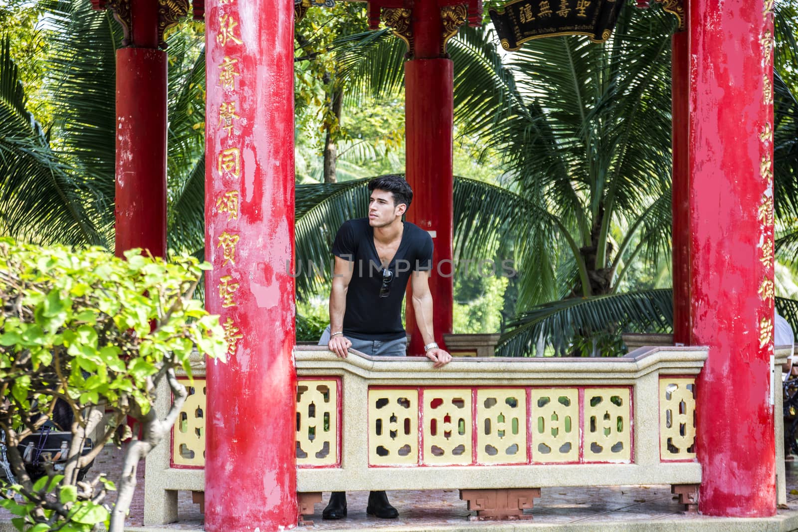 Young handsome man standing in Chinese temple in Bangkok, Thailand. Horizontal outdoors shot