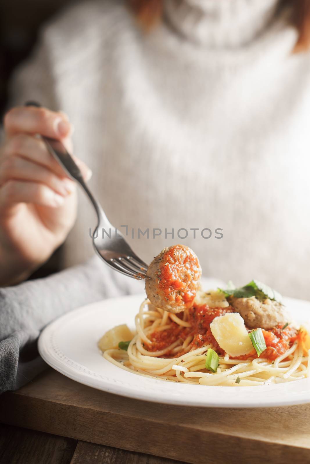 Woman eating meatballs from dish vertical