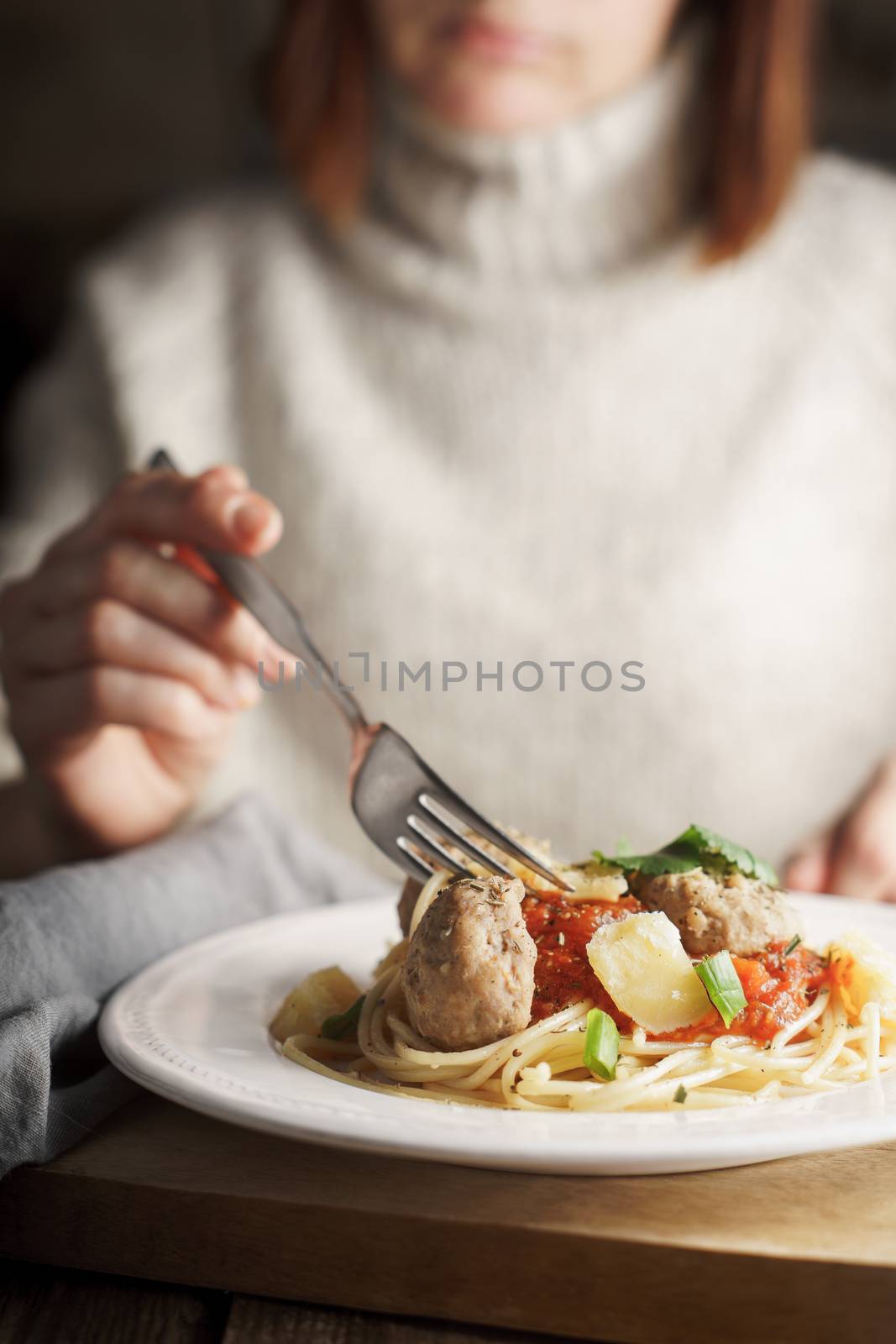 Woman eating spaghetti with meatballs vertical