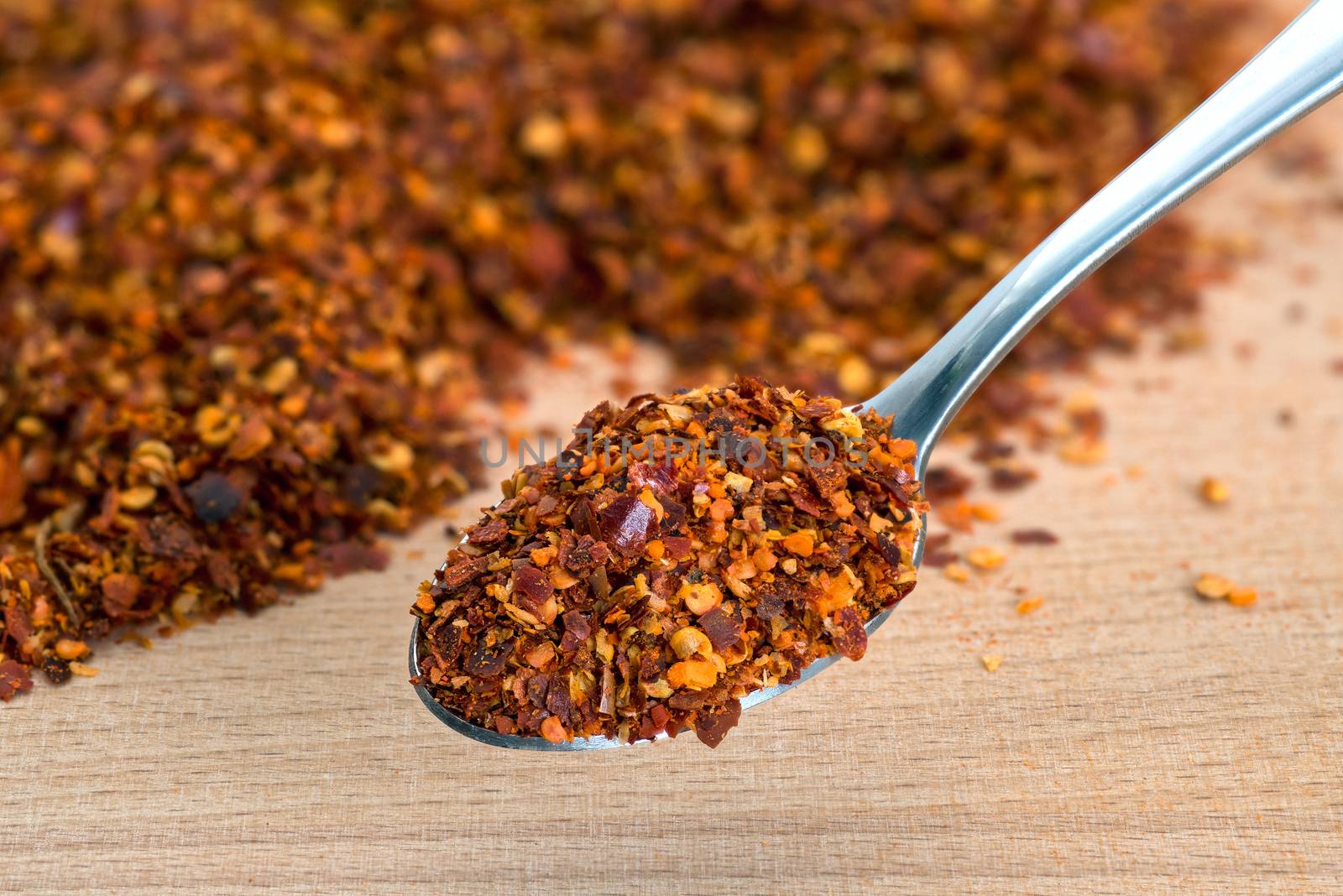 Organic hot red chili flakes made from organically grown whole red chillies on cutting board background
