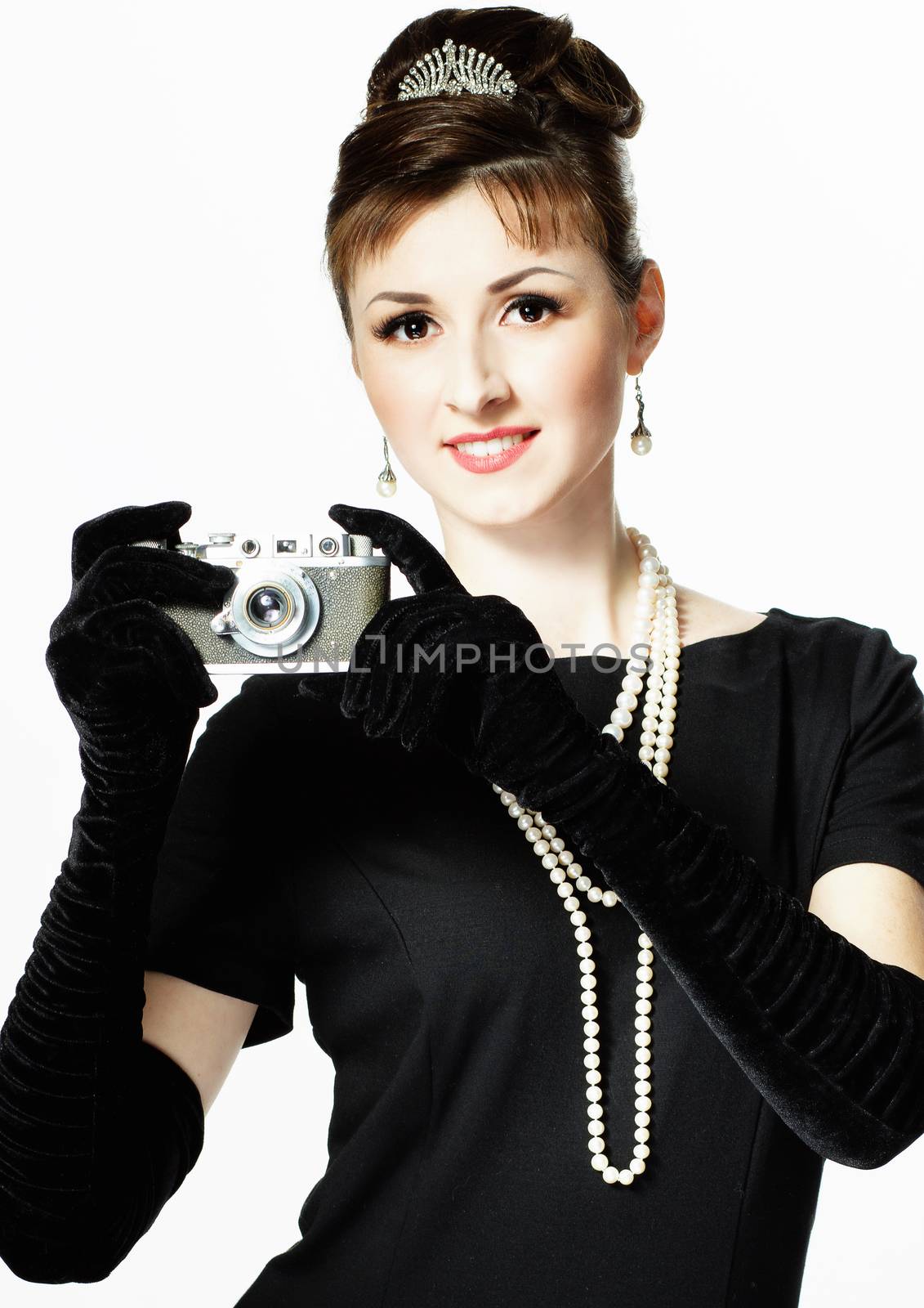 Portrait of a beautiful young elegant woman with a vintage camera isolated on white background. The girl in the image of Audrey Hepburn