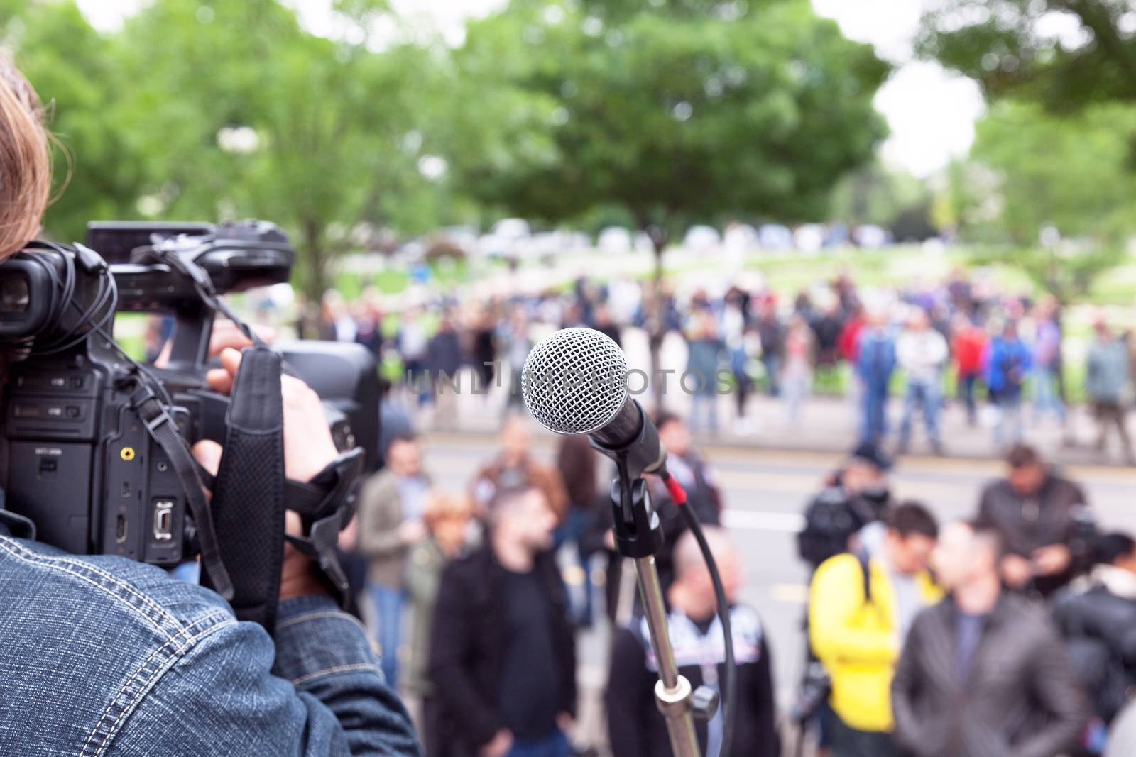 Microphone in focus, camera operator shooting blurred crowd