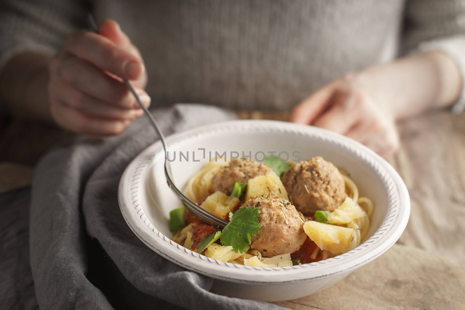 Woman eating spaghetti with meatballs from a bowl by Deniskarpenkov