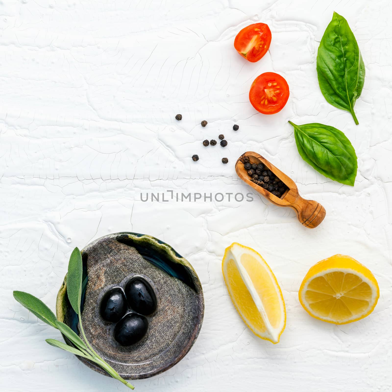 Food background with fresh herbs  tomato ,lemon slice , black pepper ,sage leaves ,sweet basil and olive oil over white wooden background  with flat lay and copy space.