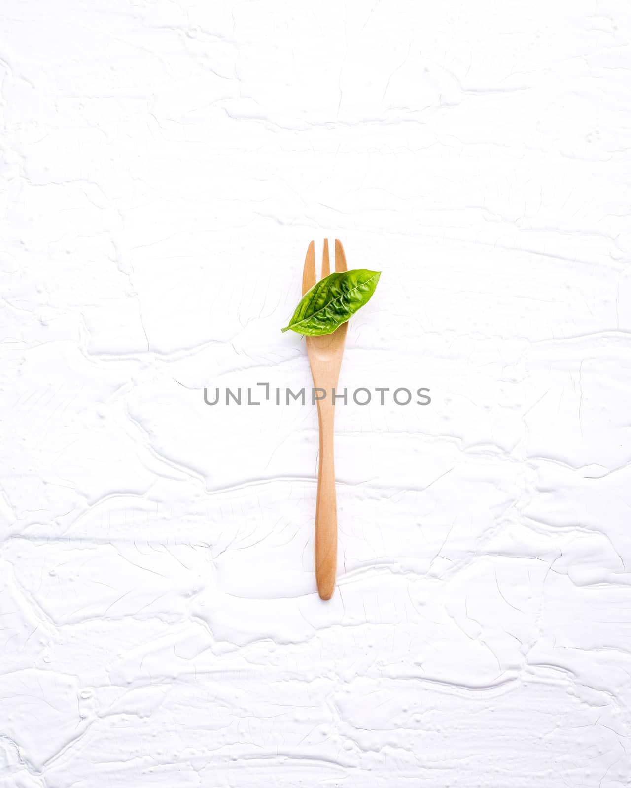 Closeup  fresh sweet basil leaves with fork  on white wooden background. Sweet basil leaves with flat lay .