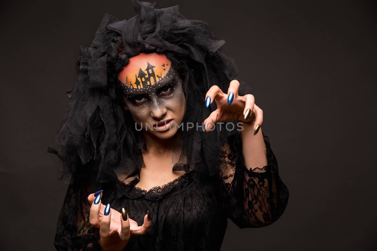 Halloween devil's bride. Portrait of young woman in dark artistic image with scary makeup, veil and terrible picture on her forehead.