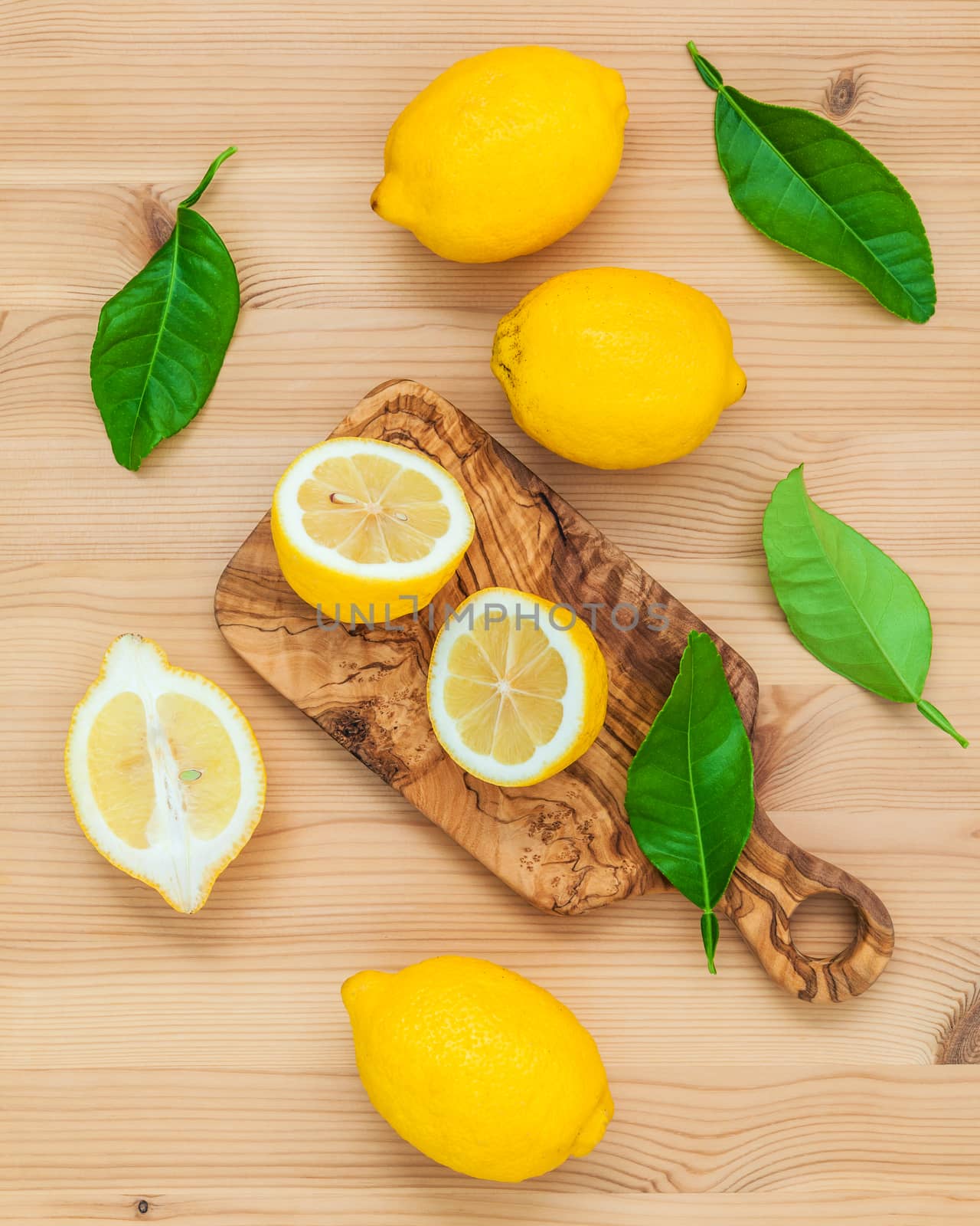 Fresh lemons and  lemons leaves on rustic wooden background. Fresh lemons and lemon slice on wooden table with flat lay.  Fresh citrus fruit background.