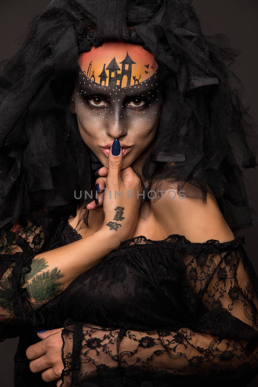 Halloween devil's bride. Portrait of young woman in dark artistic image with scary makeup, veil and terrible picture on her forehead.