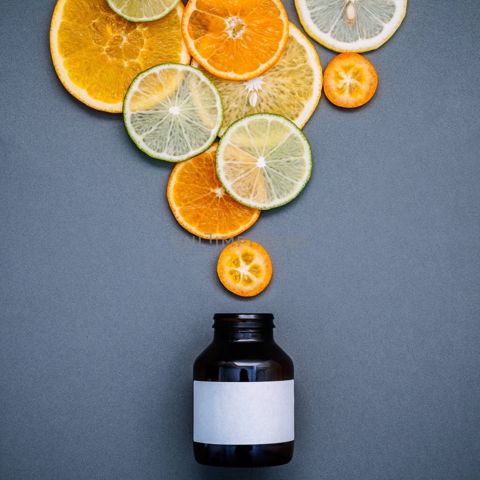 Healthy foods and medicine concept. Bottle of vitamin C and various citrus fruits. Mixed citrus fruits sliced lime,orange and lemon on gray background flat lay.