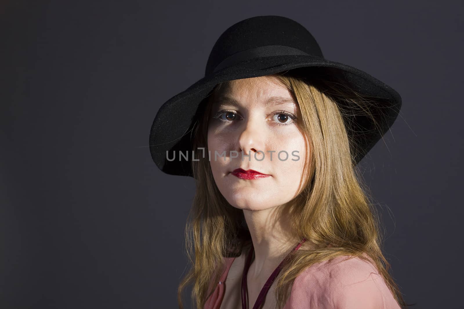 Portrait of a young woman in a hat on a black background