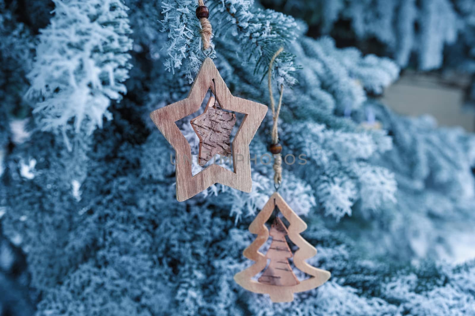 wooden Christmas toys on a beautiful snowy fir tree in winter.