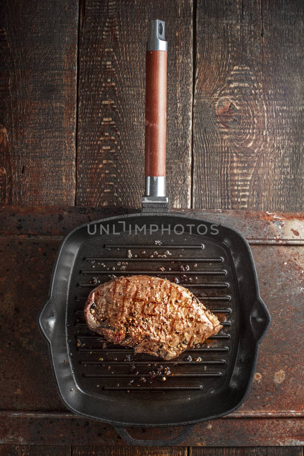 Roast beef steak in spices on pan grill on the table by Deniskarpenkov