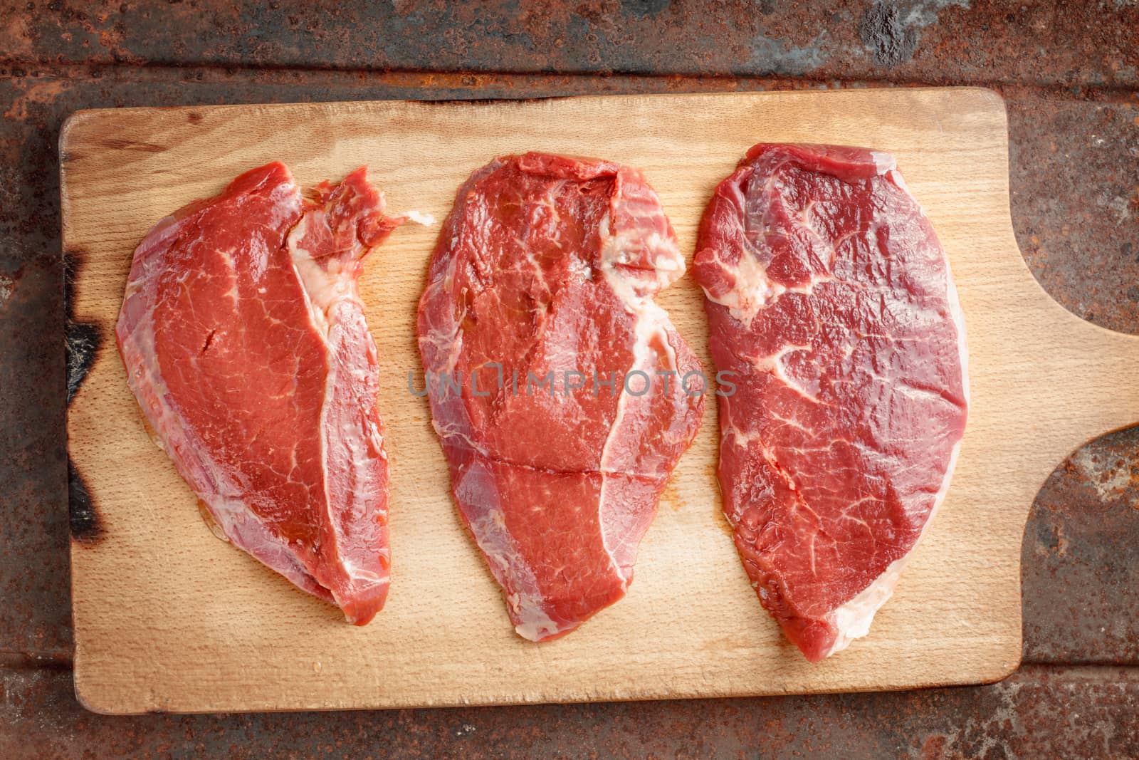 Raw beef steak on cutting board by Deniskarpenkov