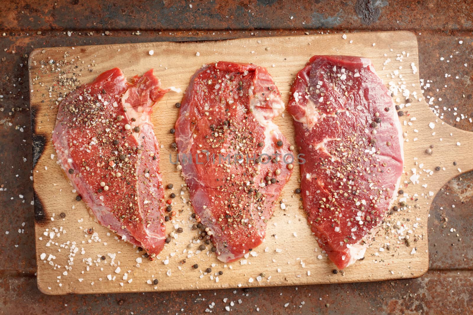 Raw beef steak and spicel on cutting board by Deniskarpenkov