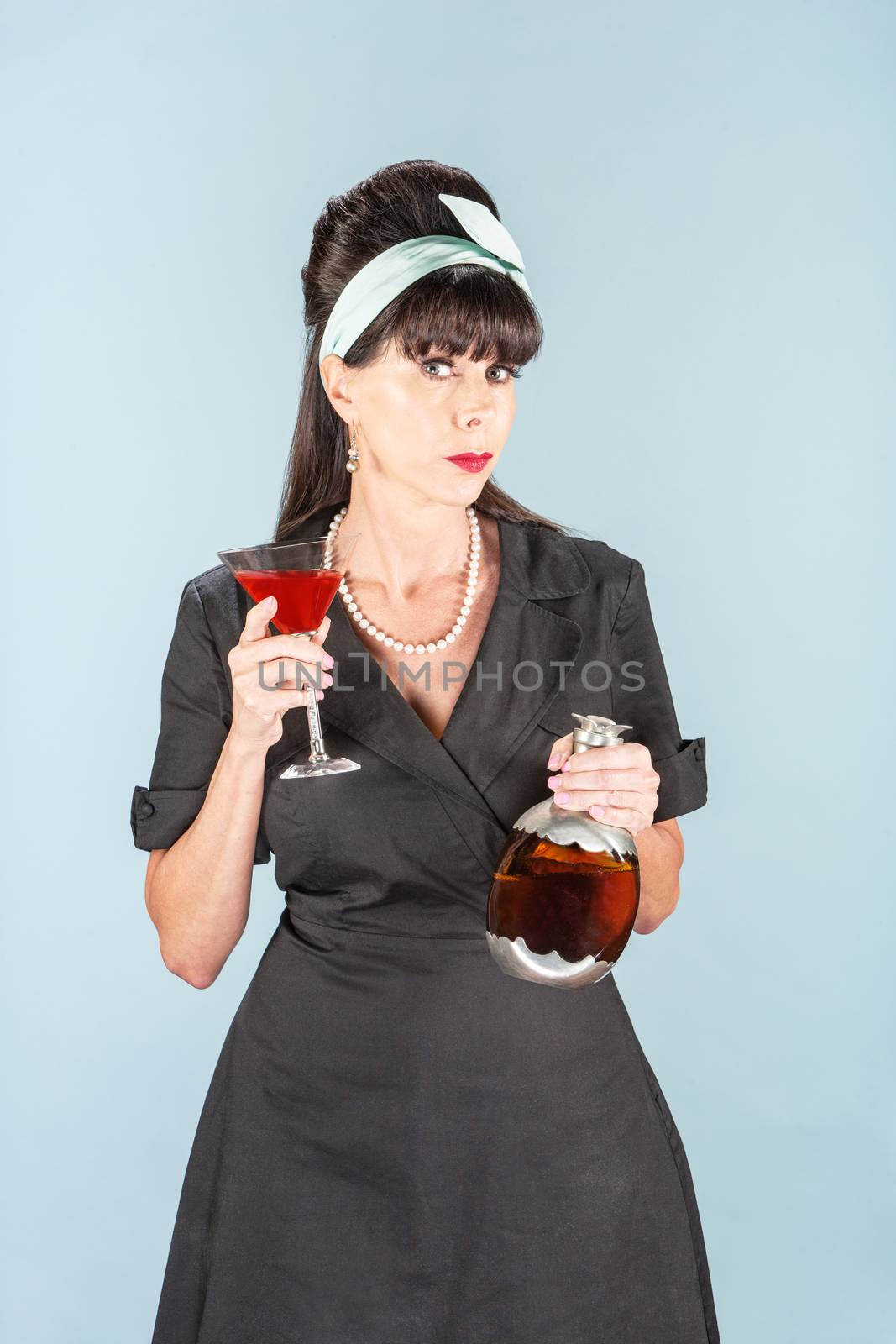 Sultry retro woman in black dress with Cosmopolitan and decanter