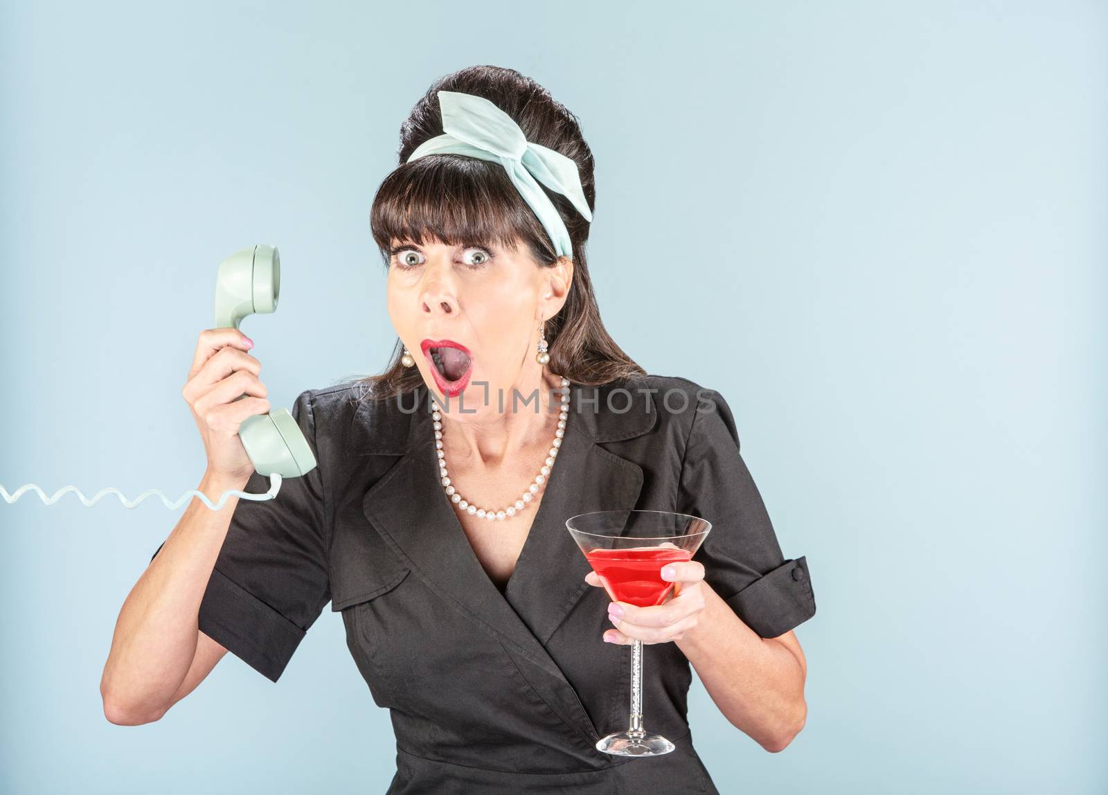 Close up on shocked retro woman in black dress with vintage phone receiver