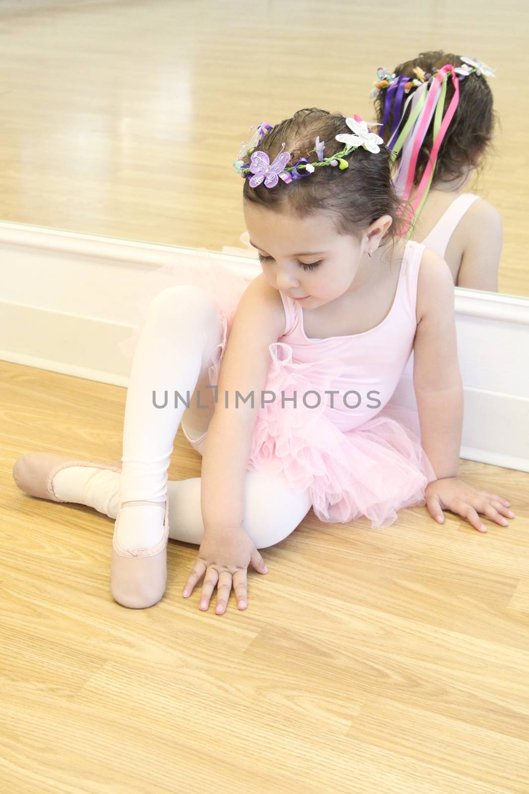 Little ballet girl sitting in front of a mirror