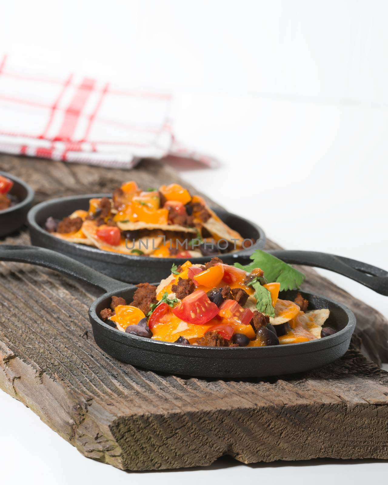 Colorful nachos served in individual cast iron fry pans.