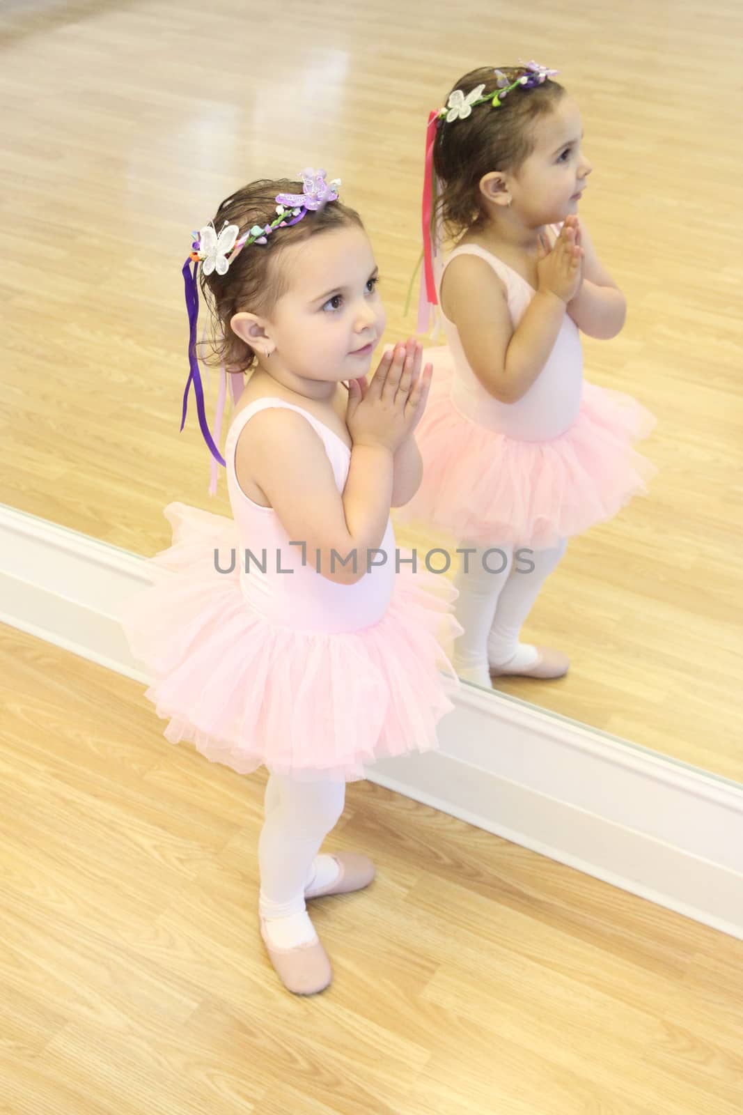 Little ballet girl standing in front of a mirror