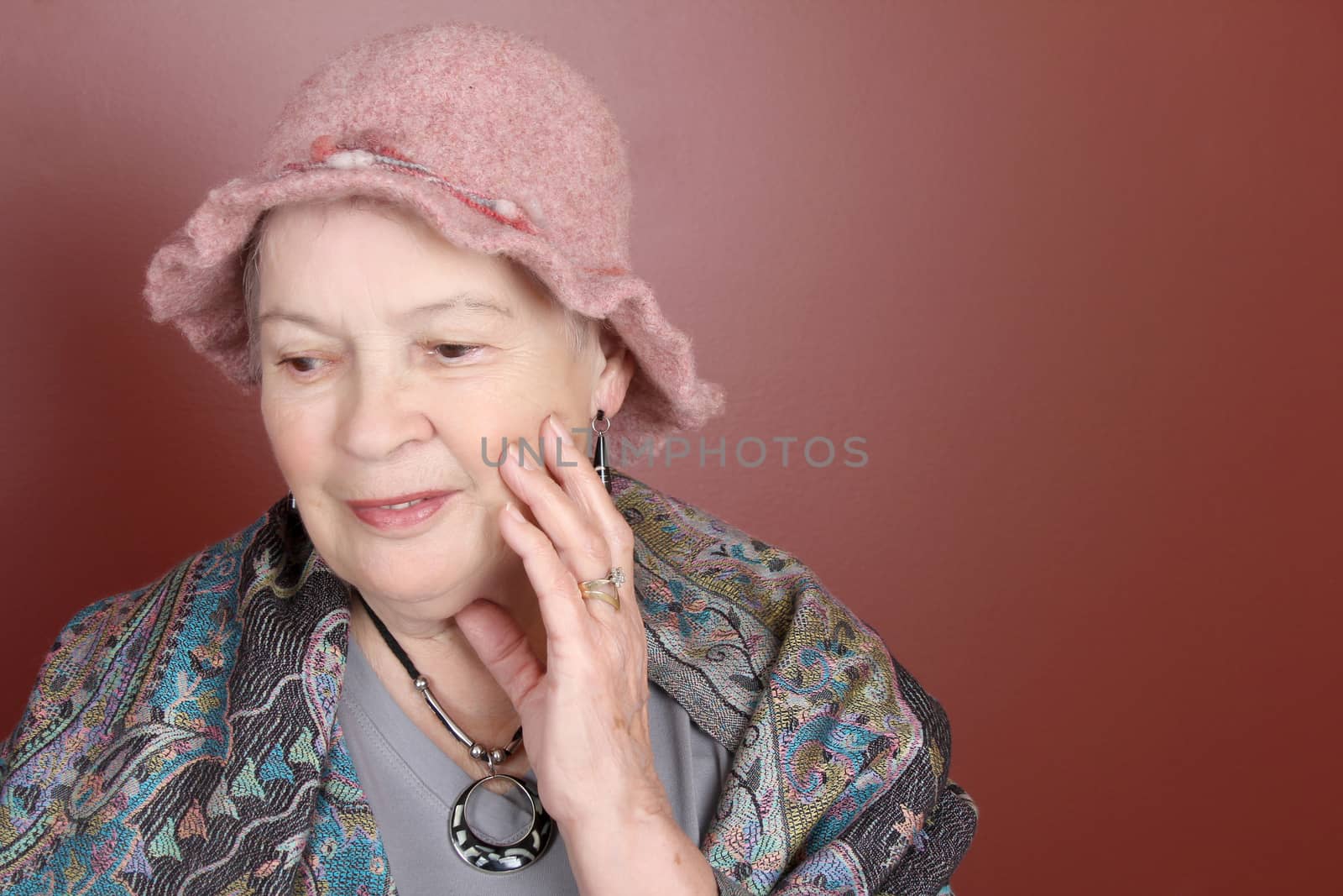 Senior lady wearing a pink hat in studio setting