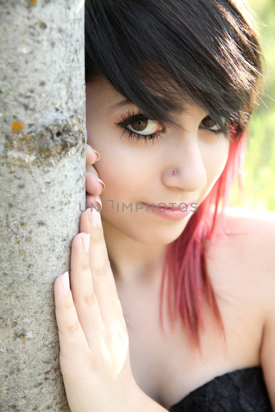 Beautiful brunette girl leaning against the trunk of a tree