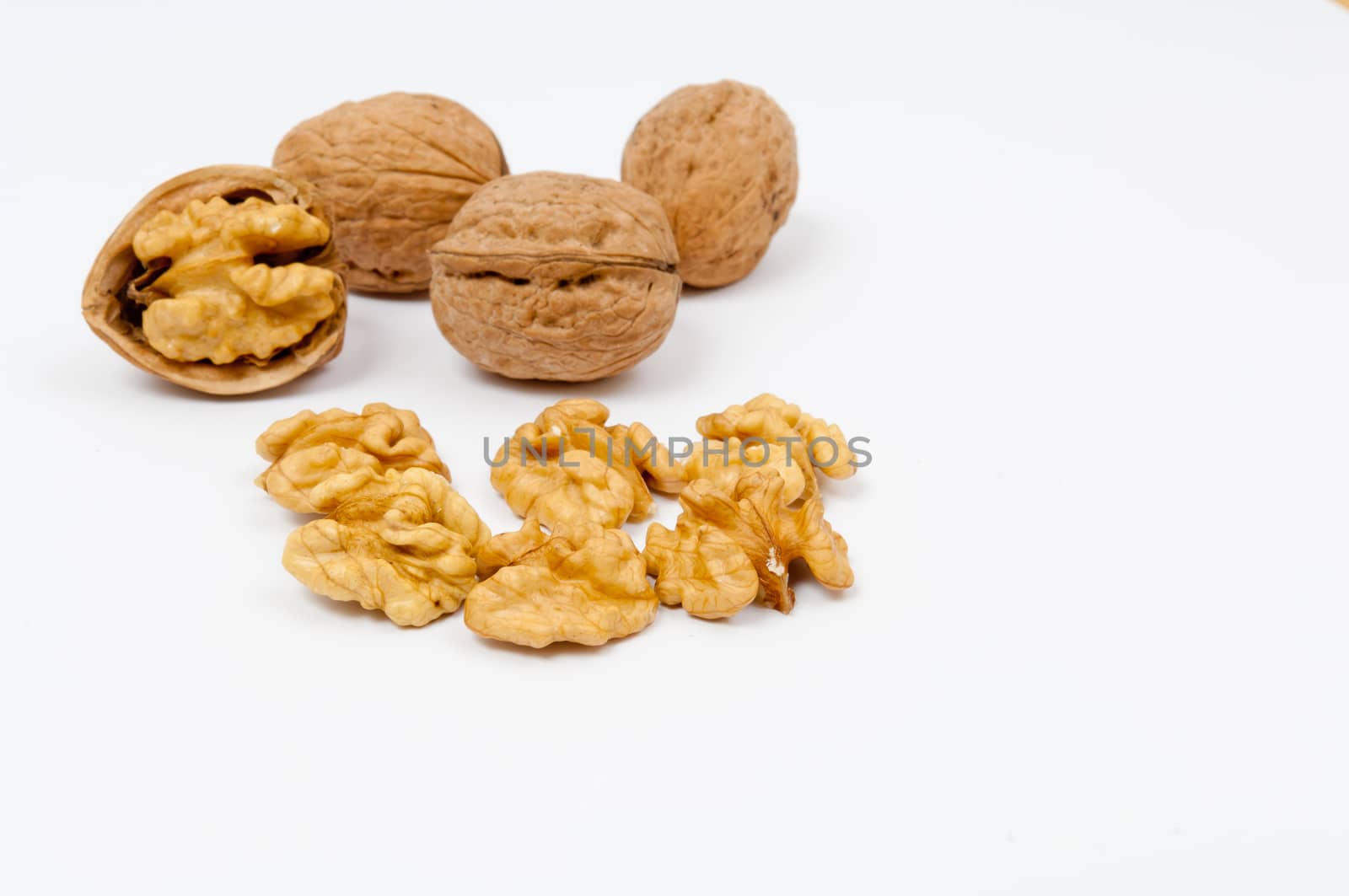 Whole walnuts and walnut kernels on white background