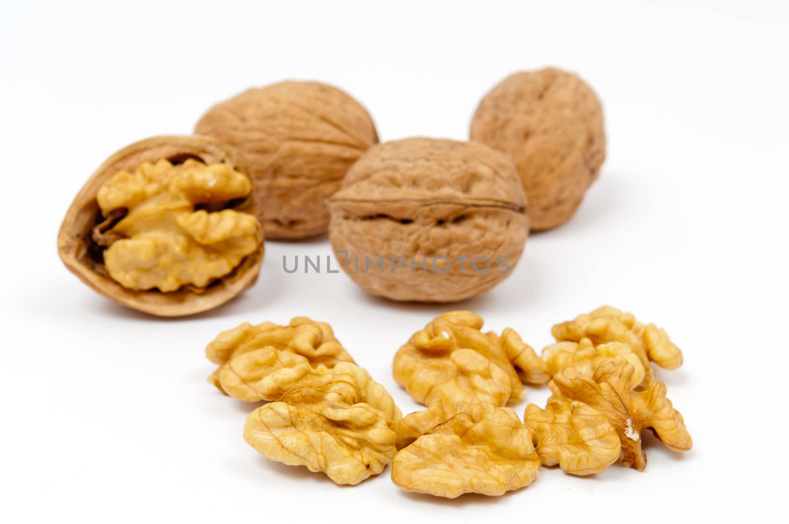 Whole walnuts and walnut kernels on white background
