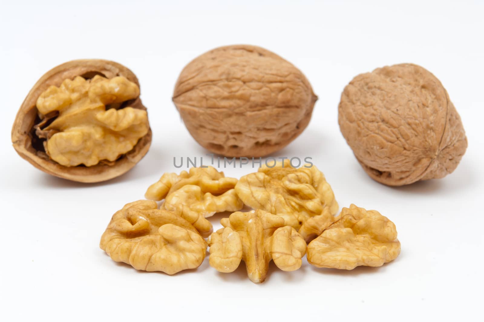 Whole walnuts and walnut kernels on white background