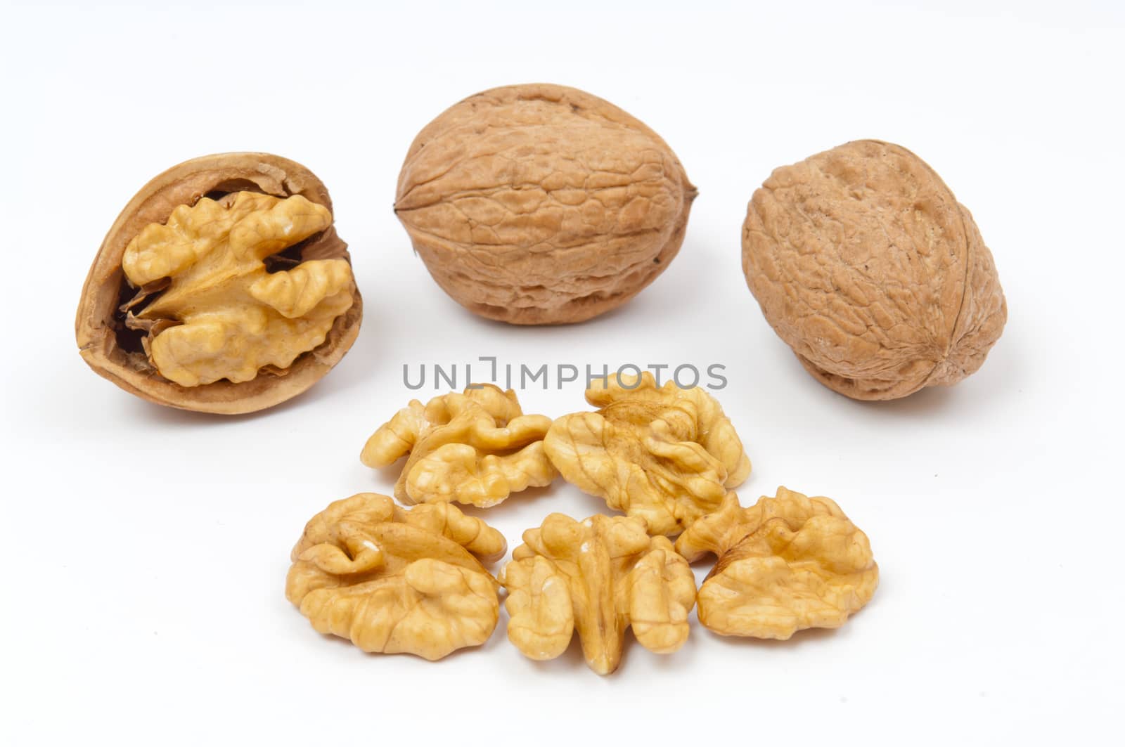 Whole walnuts and walnut kernels on white background