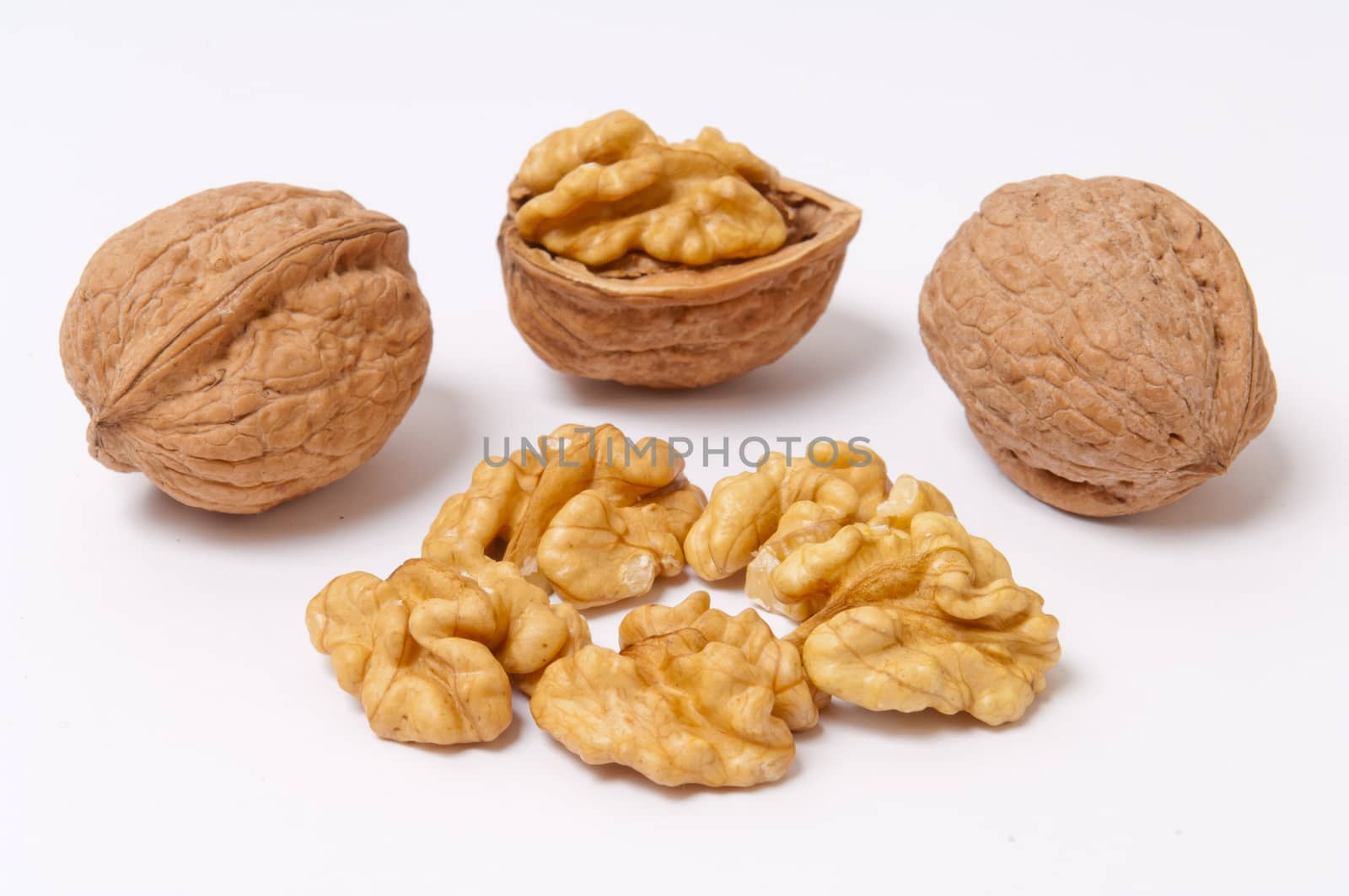 Whole walnuts and walnut kernels on white background