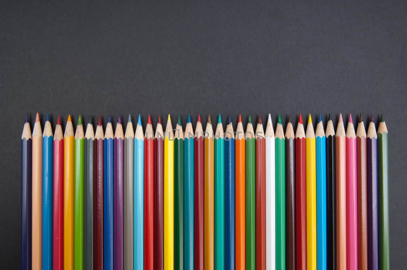 Pattern of color pencils isolated on black background close up