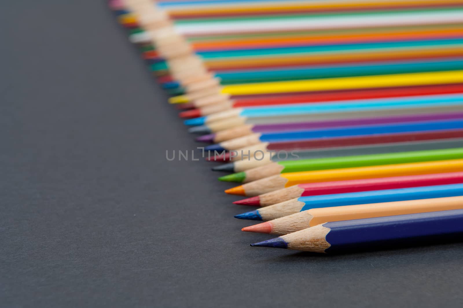 Pattern of color pencils isolated on black background close up