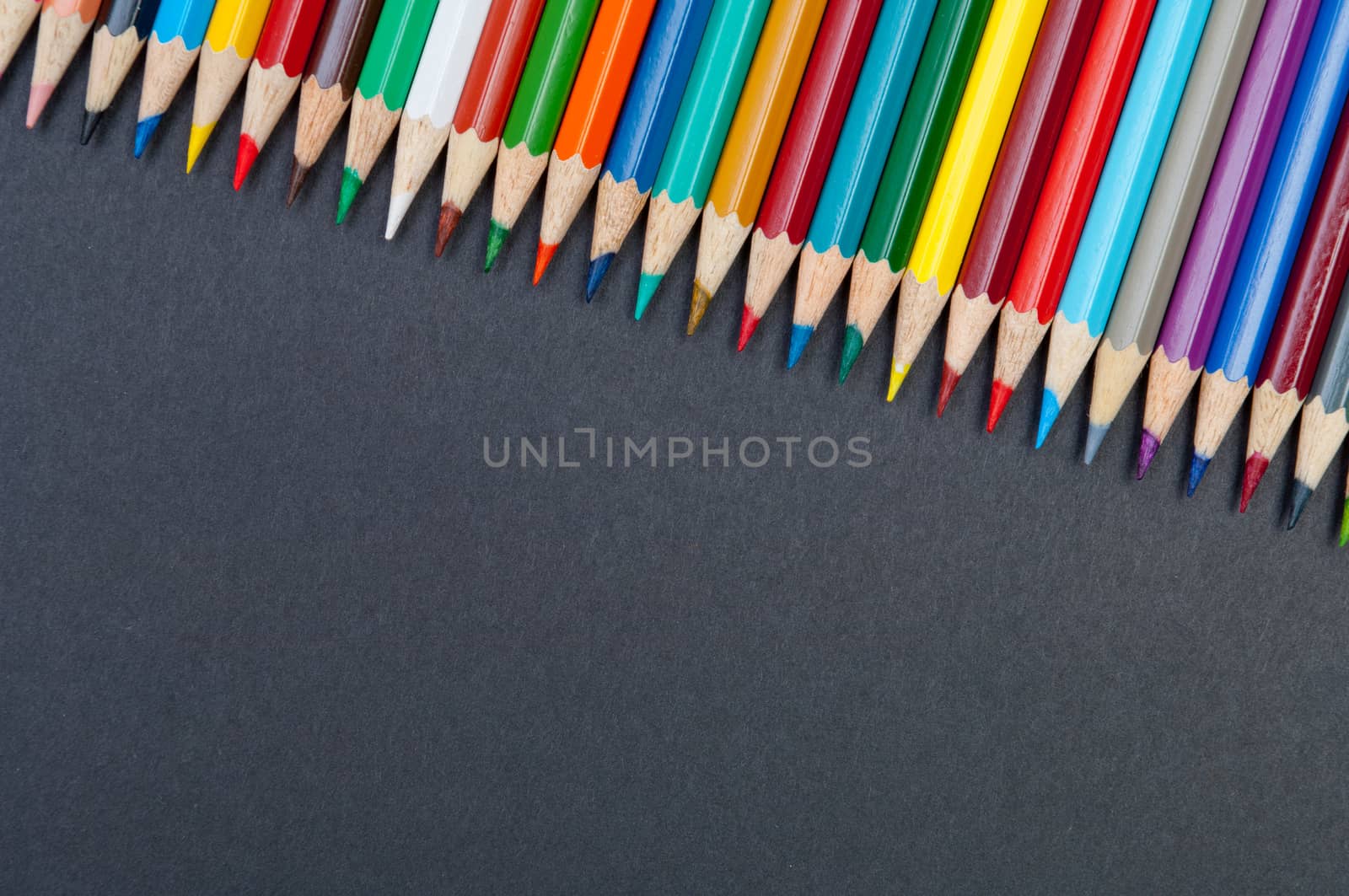 Pattern of color pencils isolated on black background close up