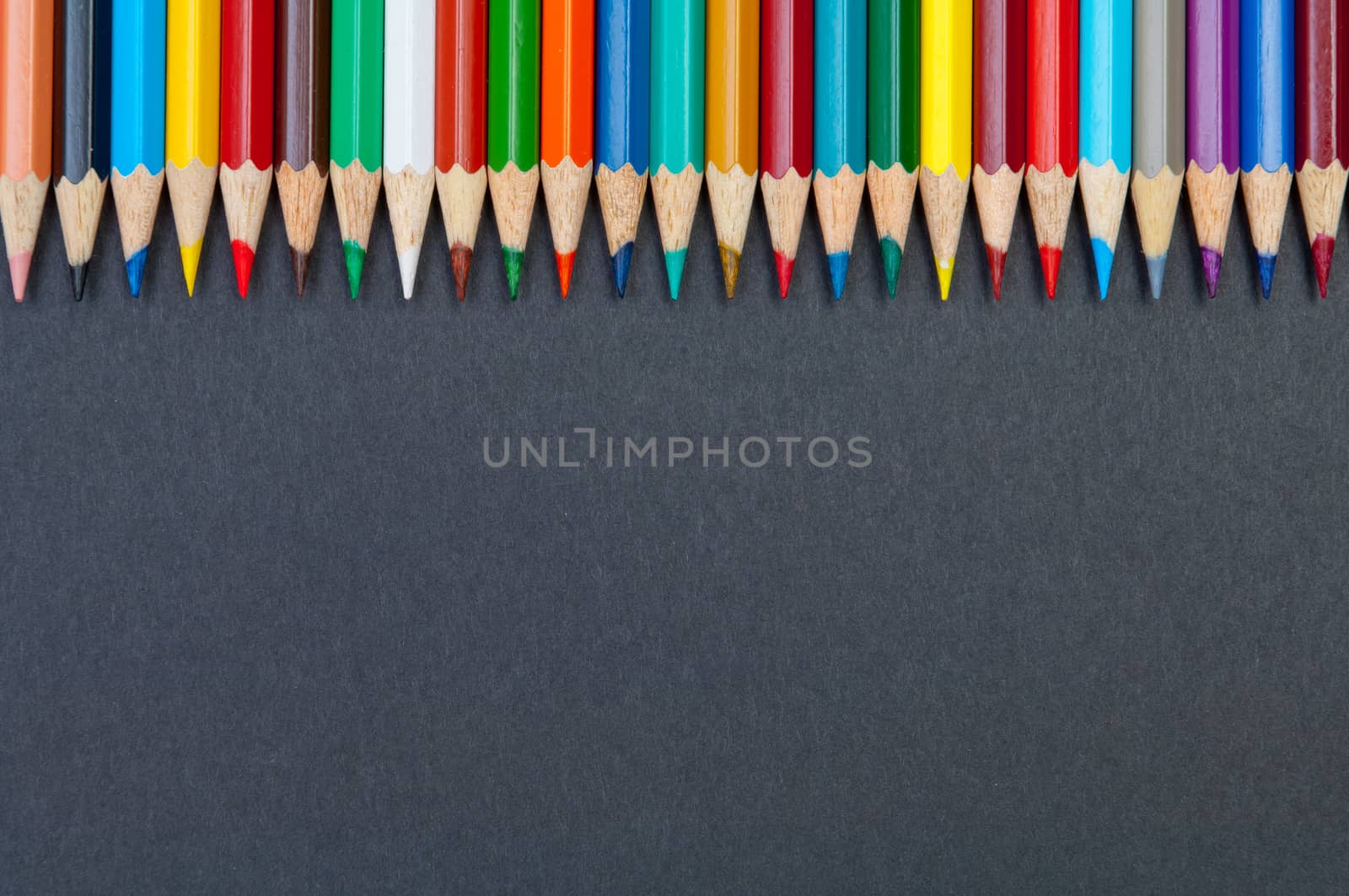 Pattern of color pencils isolated on black background close up