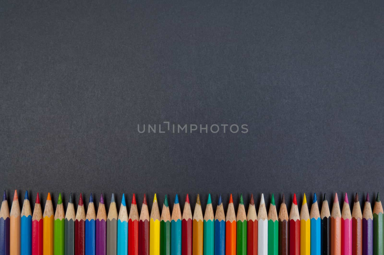 Pattern of color pencils isolated on black background close up