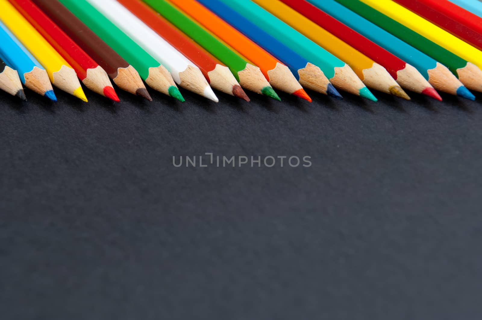 Pattern of color pencils isolated on black background close up